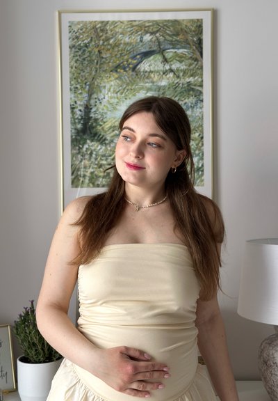 Top sin mangas de un beige claro con textura fruncida, acompañado de una falda fluida color crema. Sutiles acentos de joyería y un suave fondo interior.