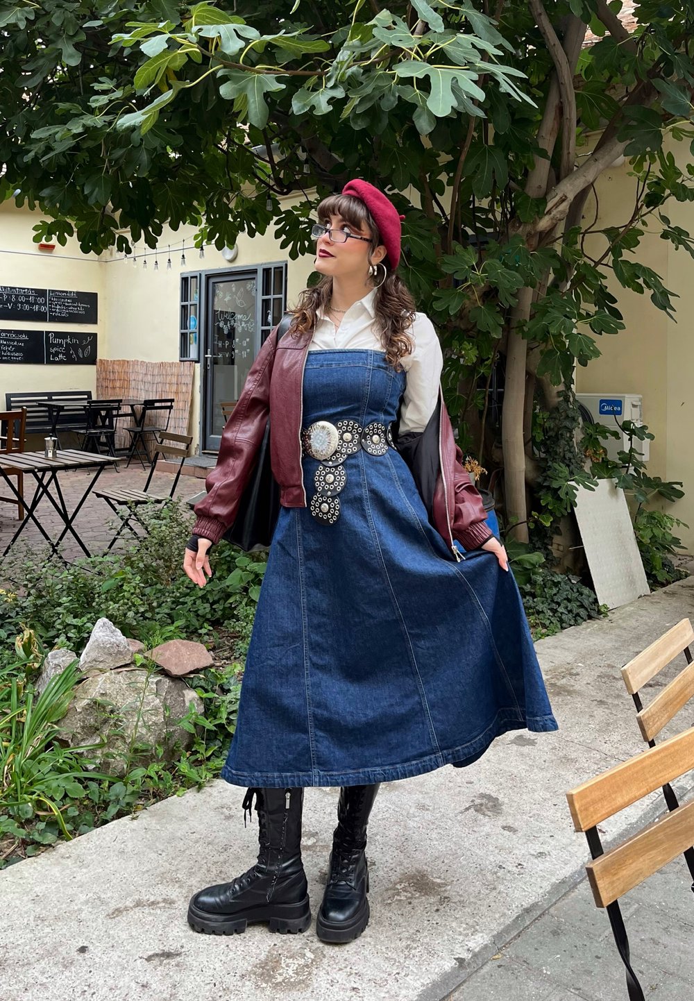Denim dress with a fitted bodice and flared skirt, paired with a maroon bomber jacket. Black combat boots and a red beret complete the look.