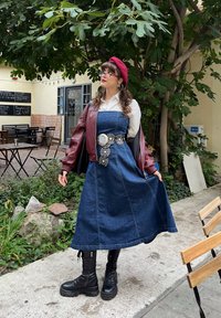 Denim dress with a fitted bodice and flared skirt, paired with a maroon bomber jacket. Black combat boots and a red beret complete the look.