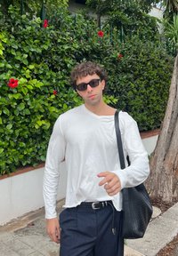 Hvid langærmet skjorte med en let løs pasform, parret med mørke stribede bukser og en sort struktureret skuldertaske.