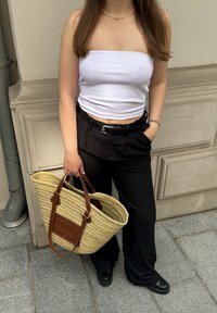 Λευκή ριμπ τρεξ ριχτή φανέλα, μαύρο παντελόνι ψηλής μέσης, πλεχτή τσάντα από σιτάρι με καφέ δερμάτινες λαβές, και μαύρες πλατφόρμες.