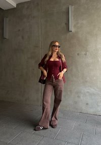 Μαρούλι εφαρμοστό τοπ με κουμπιά, oversized μαρούλι ζακέτα, καφέ καμπάνα παντελόνι και σκούρα αθλητικά. Λείες υφές; χαλαρός σχεδιασμός.