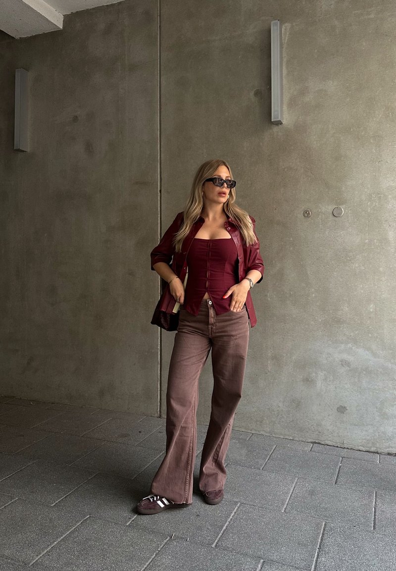 Μαρούλι εφαρμοστό τοπ με κουμπιά, oversized μαρούλι ζακέτα, καφέ καμπάνα παντελόνι και σκούρα αθλητικά. Λείες υφές; χαλαρός σχεδιασμός.
