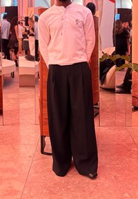 Fehér hosszú ujjú ing virágmintával, fekete bő szárú nadrággal párosítva. Simább anyag, laza szabás, minimális kiegészítők.