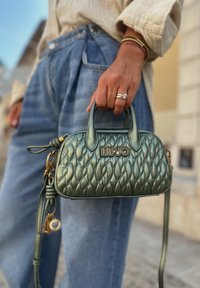 Borsa a tracolla verde trapuntata con manici superiori, tracolla staccabile, hardware dorato e dettaglio del logo sulla parte anteriore. Finitura in pelle testurizzata.
