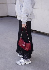 Grey hoodie, black lace skirt, red handbag with silver accents, and grey trainers. Emphasis on comfort and casual style with layered textures.