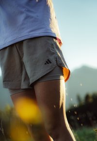 Lys grå shorts med indersøm, der har sort Adidas logo. Materialet synes åndbart og velegnet til sportstøj.