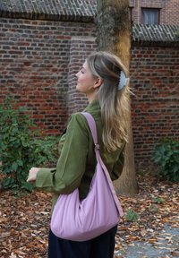 Rosa, ledig håndveske laget av mykt materiale, med en enkelt stropp. Designet er glatt uten synlige mønstre eller metallbeslag.