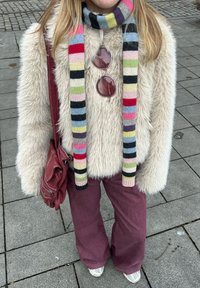 Jachetă crem din blană artificială, eșarfă cu dungi multicolore, pantaloni largi vișinii, ochelari de soare rotunzi roz și o geantă de umăr marsala.