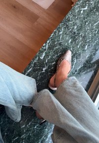 Ballerines à bout pointu avec un motif serpent, des accents métalliques et une ouverture à l'arrière. Portées avec un jean en jean bleu clair sur une surface en marbre.
