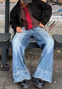 Traperice s velikim, raširenim krojem; svijetloplave boje s izblijedjelim područjima i detaljima šavova. Crne cipele, smeđa košulja i crvena kravata.