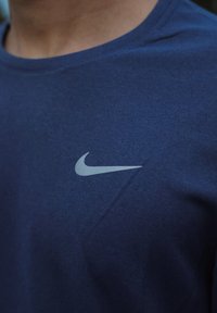 T-shirt Nike bleu marine en tissu texturé, avec un logo swoosh gris clair sur le côté gauche de la poitrine, col rond.