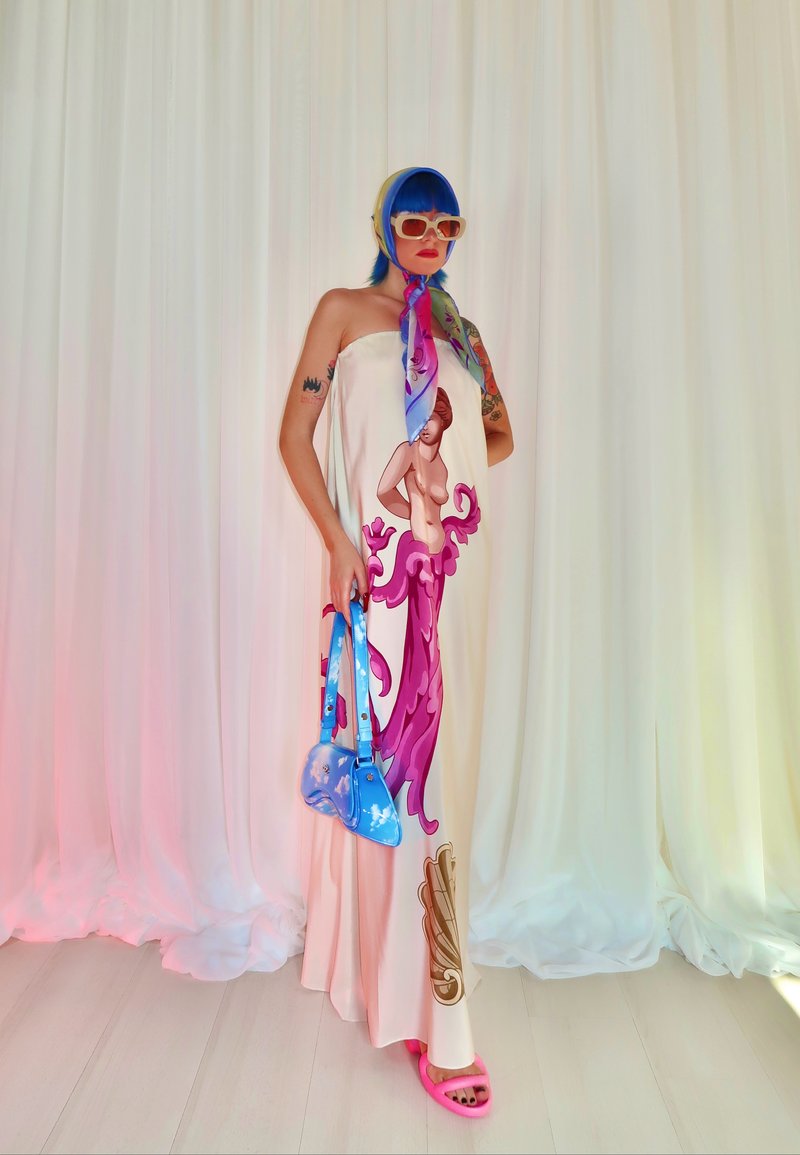 Vestido sem alças com uma ilustração central de uma figura com detalhes em rosa, combinado com uma bolsa azul e sandálias rosas, contra um fundo texturizado.