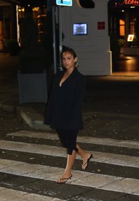 Svart oversized blazer over en svart topp, kombinert med svarte leggings og svarte flip-flops, som går over et fotgjengerfelt om natten.