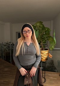 Bluza gri cu mâneci lungi, cu relief și nasturi, asortată cu pantaloni negri. Include o bandană neagră, ochelari rotunzi și un ghiveci de plante cu model auriu.