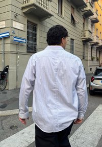 Camicia button-up a righe blu chiaro e bianco con maniche lunghe, vestibilità comoda e orlo arrotondato. La camicia presenta bottoni ai polsini discreti e un colletto classico.