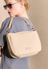 Beige Leder Umhängetasche mit einer strukturierten Oberfläche und silbernen Beschlägen. Verfügt über eine geräumige Form und einen langen, abnehmbaren Gurt.