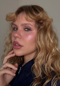 ポートレートの人物は、波状の明るい茶色の髪を持ち、濃紺のジャケットを着ています。肌は露出した質感で、柔らかい特徴とそばかすを強調しています。