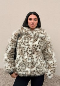 Leopard print faux fur jacket featuring a high collar, long sleeves, and a plush texture, paired with black leggings.