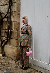 Blomstermønstrede grønne jakkesæt med en skræddersyet blazer og brede bukser, parret med en lille lyserød håndtaske og platform sko.