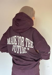 Sweatshirt roxa oversized com uma grande impressão branca a dizer "FEITO PARA O FUTURO." Tecido macio, com capuz e punhos ribateados.