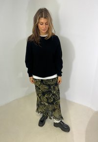 Black knitted jumper, white layered shirt, floral patterned skirt in green and black, and chunky black platform boots with laces.
