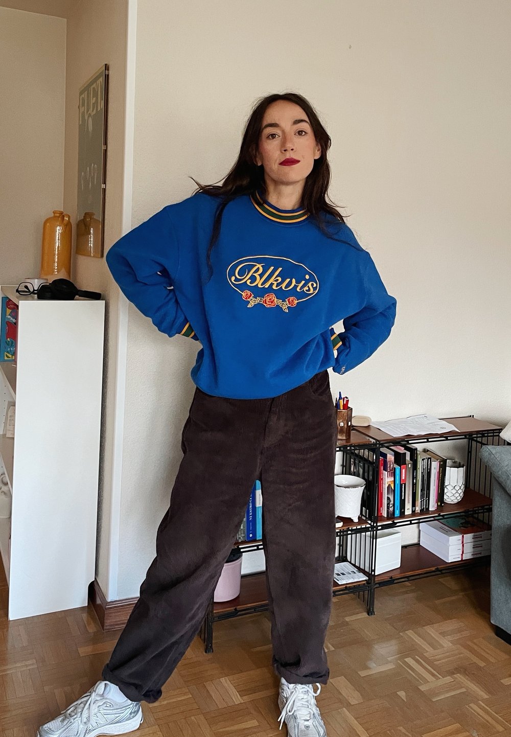 Μπλε βαμβακερό φούτερ με το κεντημένο "Blkvis" σε κίτρινο και κόκκινα τριαντάφυλλα, συνδυασμένο με καφέ βελουτέ παντελόνι και λευκά αθλητικά παπούτσια.