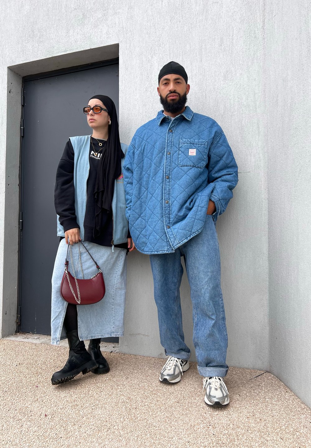 Τζάκετ από τζιν με επένδυση και τσέπη, συνδυασμένο με μαύρο πουκάμισο. Τζιν φούστα και μαύρες μπότες αριστερά. Φόντο με γκρίζο τοίχο.