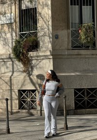 Ensemble gris en deux pièces composé d'un haut court avec des manches découpées et un pantalon évasé, associé à un sac à épaule marron et des baskets.