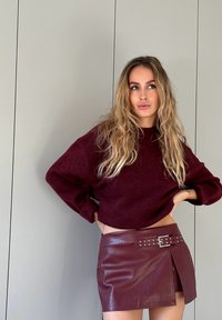 Burgundy uldet cropped sweater parret med en burgundy kunstlæder mini skirt med en sidelukning og nitter dekor.