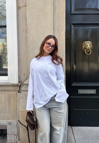 Langærmet hvid skjorte med afslappet pasform, parret med lysegrå denim bukser med sidelommer. Mørkebrun crossbody taske med hardware.