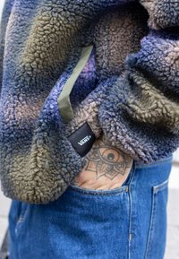 Mikina z flísu s farebným vzorom v purpurovej a khaki farbe, s logovou visačkou, mäkkou textúrou a skrytými vreckami.