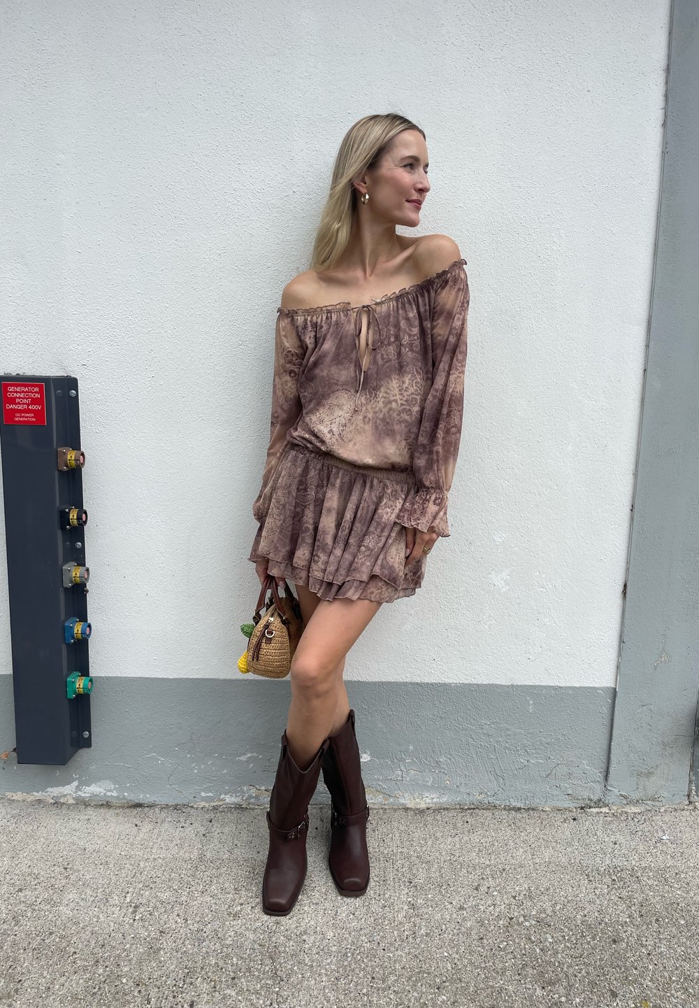 Blouse marron à épaules dénudées avec un détail à nouer, mini-jupe froncée et bottes de cowboy marron jusqu'aux genoux. Comprend également un petit sac à main tissé.