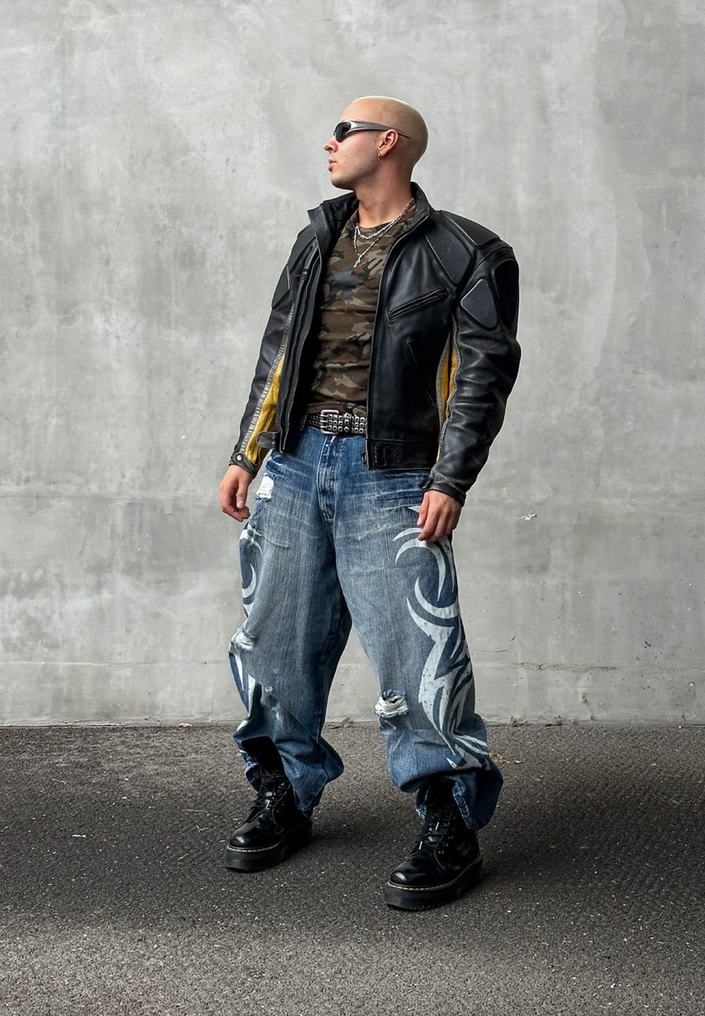 Μαύρο δερμάτινο μπουφάν με κίτρινες λεπτομέρειες, παραλλαγής πουκάμισο, φθαρμένα μπλε τζιν με λευκά φυλετικά σχέδια και μαύρες πλατφόρμες μποτίνια.