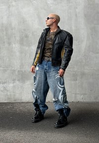 Μαύρο δερμάτινο μπουφάν με κίτρινες λεπτομέρειες, παραλλαγής πουκάμισο, φθαρμένα μπλε τζιν με λευκά φυλετικά σχέδια και μαύρες πλατφόρμες μποτίνια.