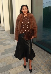 Brun prickig topp, brun pälsjacka, svart läderkjol, brun kuvertväska, svarta spetsiga klackar. Mjuka texturer och kontrasterande färger.