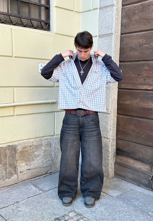 Kortärmad, rutig skjorta i ljusblått och vitt, lager på en svart långärmad skjorta, kombinerat med löst sittande mörka denimjeans.