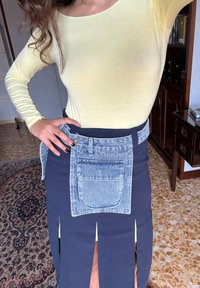 Žlutý top s dlouhým rukávem zkombinovaný s tmavě modrou sukní s denimovou kapsou a bočními rozparky. Hladký materiál, přiléhavý střih a ležérní styl.