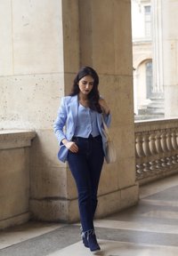 Lysblå blazer over en matchende bluse, parret med mørkeblå højtaljede jeans. En hvid håndtaske og mørke ankelstøvler fuldender outfittet.