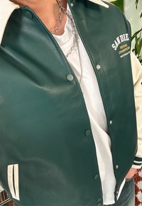 Grüne und crèmefarbene Leder-Collegejacke mit Druckknopfverschlüssen, mit "SAN DIEGO" in Weiß gestickt und gestreiften Akzenten an den Bündchen.