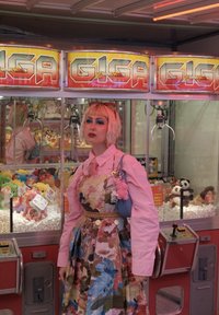 Ein Greifautomat mit der Aufschrift "GIGA" und leuchtend gelben und roten Grafiken. Bunte Plüschtiere sind hinter Glas sichtbar, vor einem pinken und grauen Hintergrund.