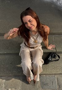 Combinaison beige texturée avec une taille cintrée, colliers en or superposés et un sac à main noir. Talons aiguilles à imprimé léopard et lunettes de soleil.