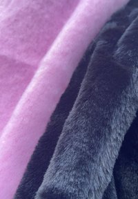 Rosa og sorte bløde stoffer er lagdelt, med en fluffy tekstur på den sorte side og en glat overflade på den rosa side.