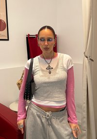 Hall halli topp helel roosa pika varrukaga särgi peal, kombineeritud hallide dressipükstega. Must käekott naelutustega. Prillid ja kihilised ehte detailid.