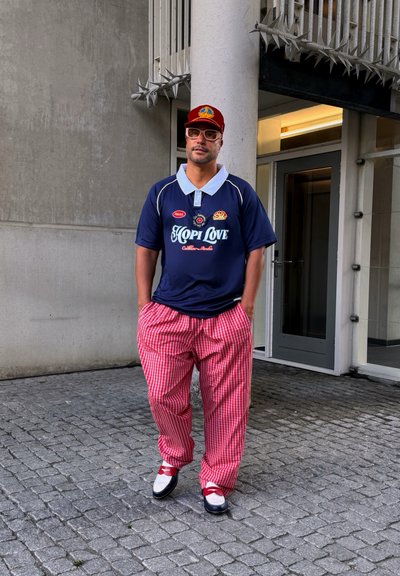 Camisa de polo azul marino con cuello blanco y texto "HOPI LOVE"; pantalones sueltos a cuadros rojos y blancos; zapatos en blanco y negro con acentos rojos.