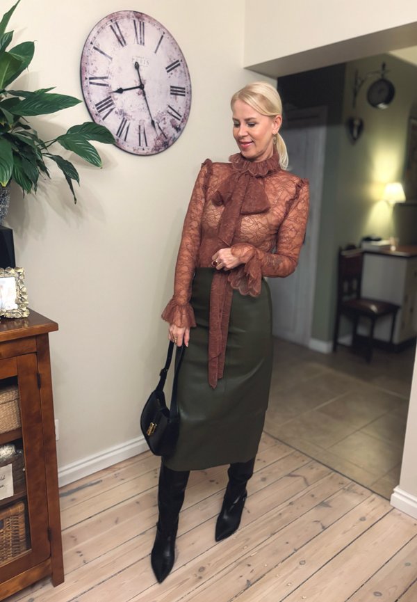 Transparent lace top in rust, featuring a bow and ruffled sleeves, paired with a fitted olive green skirt and black thigh-high boots.