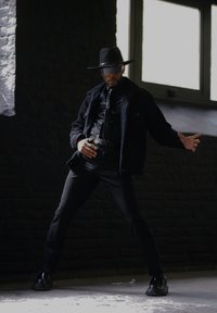 Μαύρο σακάκι από μείγματα μαλλιού με λεπτομέρειες από γούνα, στενή μαύρη μπλούζα, παντελόνια και γυαλιστερά παπούτσια. Καπέλο με φαρδύ γείσο και σκούρα γυαλιά ηλίου.