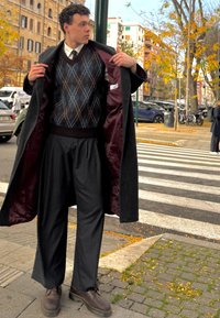Tumša virsjaka ar burgundijas sarkanas krāsas oderi, rakstains vestes tumši zilā un brūnā krāsā, svītrains bikses un brūnas mežģīņu kurpes.