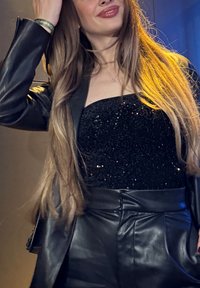 Black sequined top with a strapless design, paired with high-waisted black leather trousers. The look is completed with a tailored black blazer.