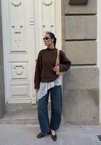 Rudas pūkuota megztinis uždėtas ant balto nėriniuoto viršaus, derinamas su aukštomis tamprėmis iš tamsaus džinsinio audinio ir rudomis loafer bateliais, papildant mažomis geltonomis rankinėmis.